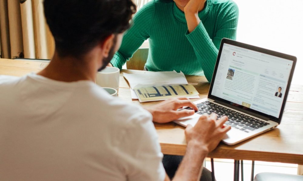 two people at a table, with laptops