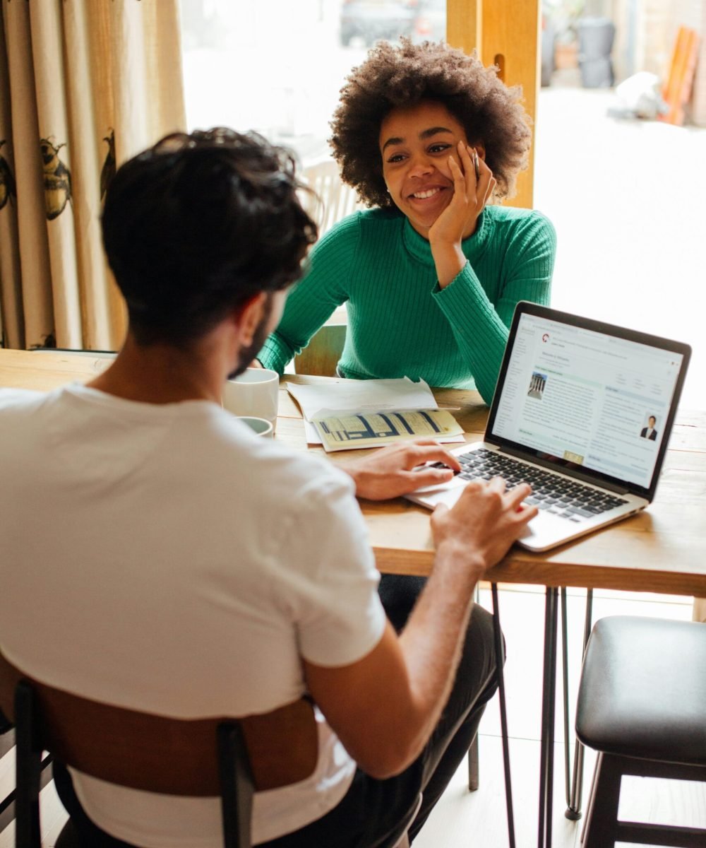 two people at a table, with laptops